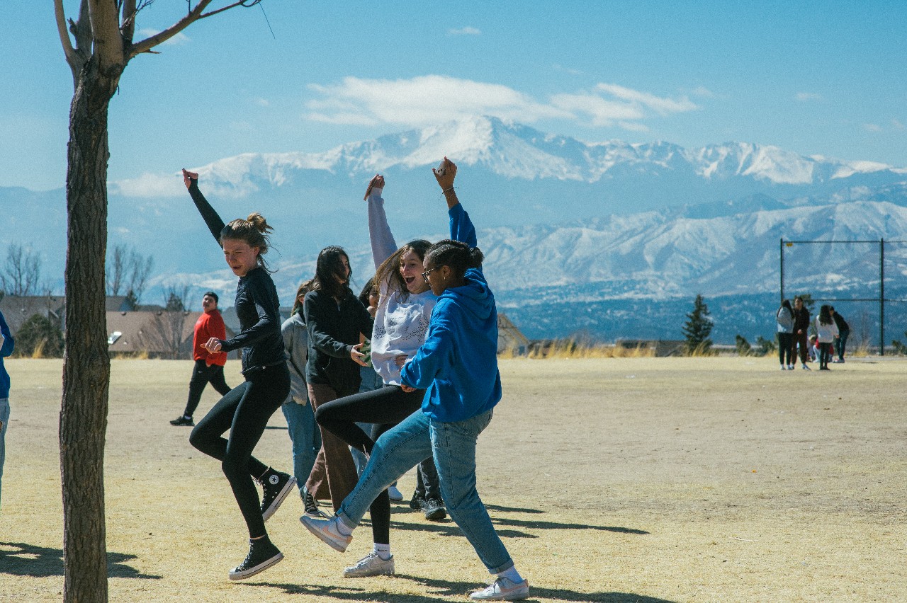 Students on the Mountain Ridge athletic field with Pikes Peak in the background.